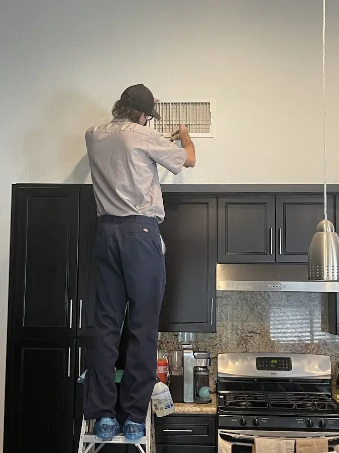 Technician inspecting an air vent during HVAC service in San Mateo